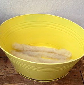 Meagre selection of rolags in the bottom of my BRIGHT YELLOW rolag tub.