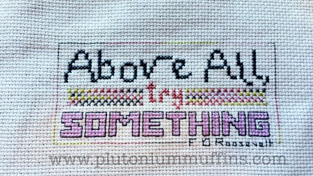 The stitched piece, with DMC Coloris on either side of the word "try".