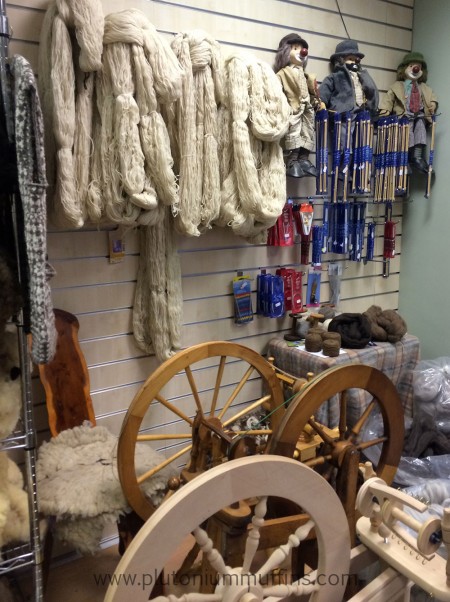 Skeins of yarn and spinning wheels, with some notions on the right.